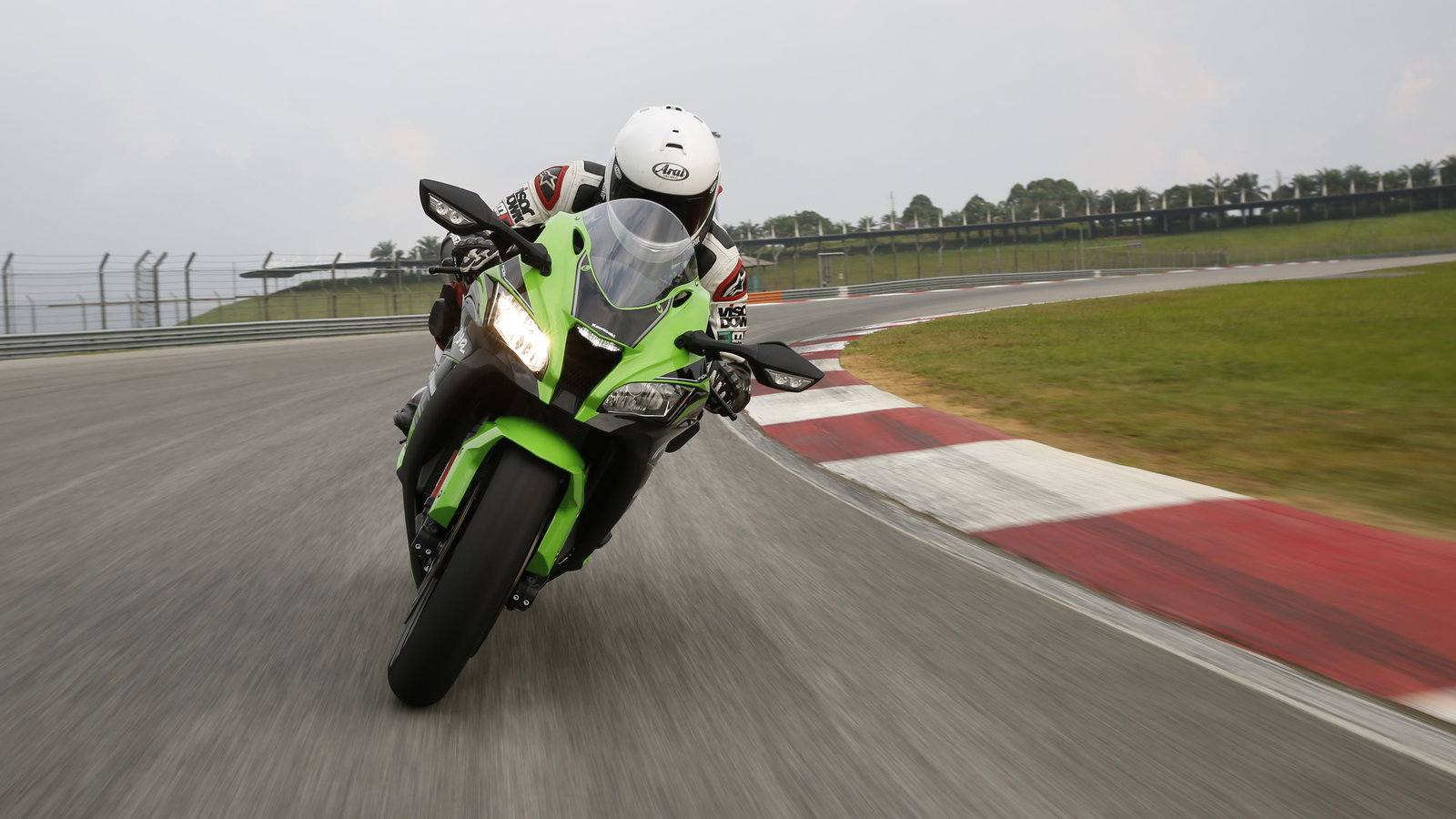 A front-on picture of a green and black 2016 Kawasaki ZX-10R being ridden on a track